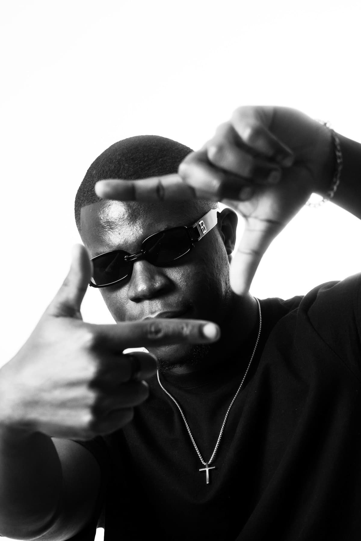 TAPIWA in black and white, sunglasses on, framing his face with his hands